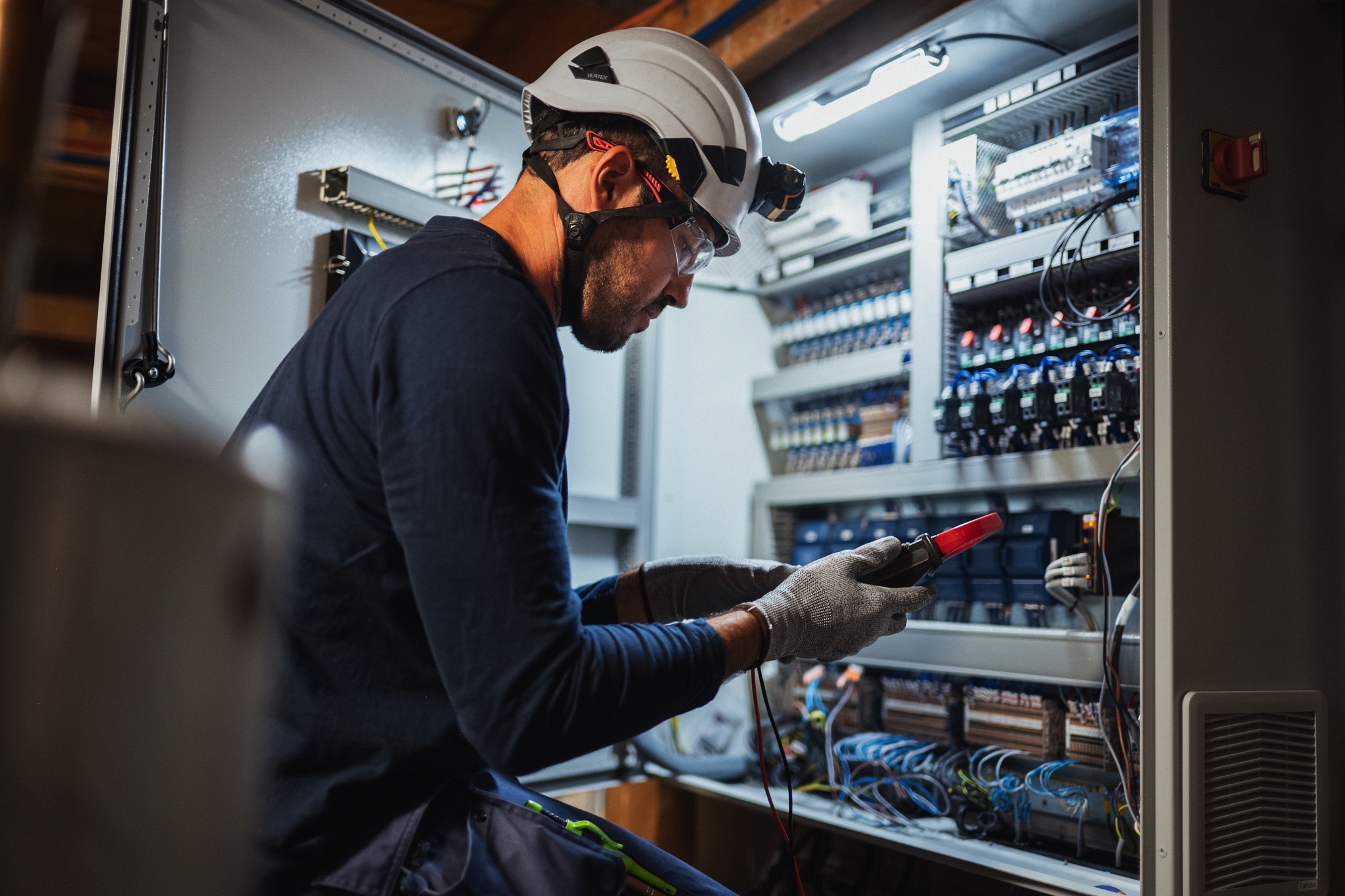 Technicien réalisant des opérations de contrôle et de paramétrage sur une armoire de Gestion Technique du Bâtiment (GTB).