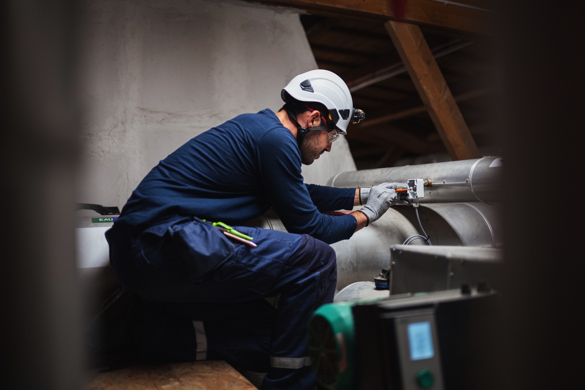 Technicien réalisant le raccordement et le paramétrage d’un équipement connecté de Gestion Technique du Bâtiment (GTB) dans un local technique.