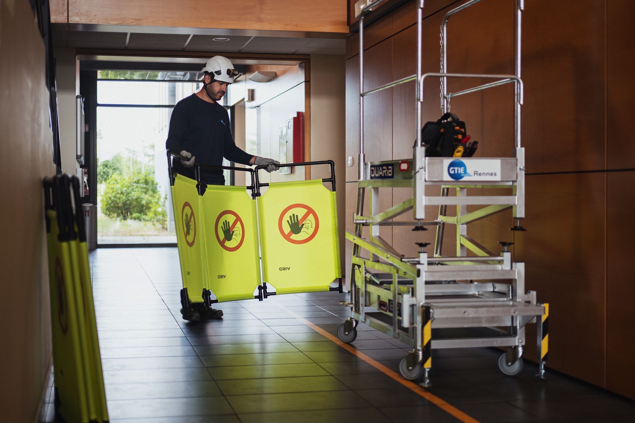 Technicien installant un balisage de sécurité autour d’une zone d’intervention technique à proximité d’une plateforme de travail mobile.