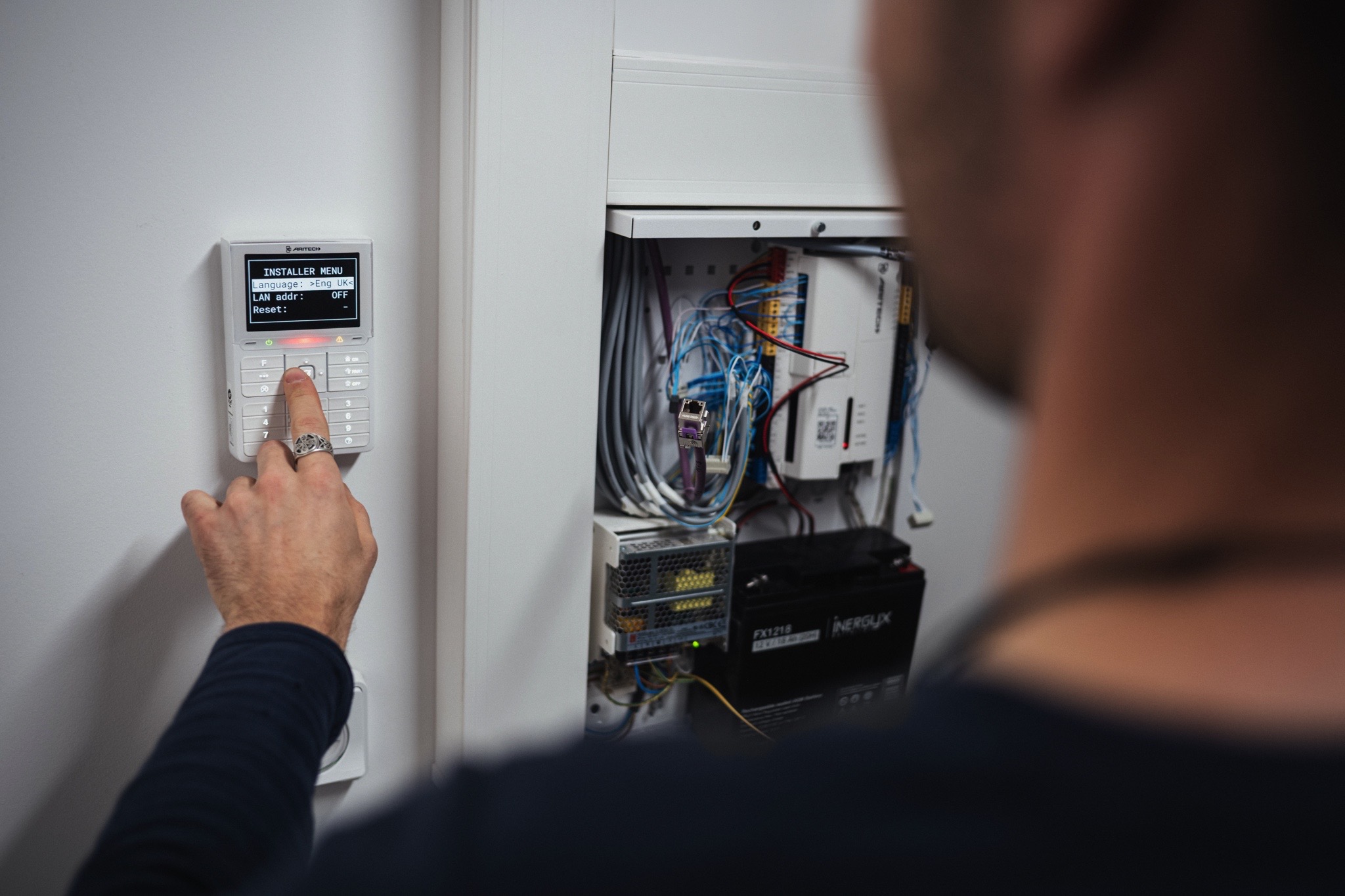 Technicien configurant un système de contrôle d’accès avec clavier de commande et coffret de sécurité électronique dans un bâtiment tertiaire.