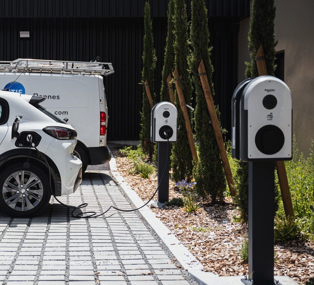 Véhicule électrique en cours de recharge sur une borne IRVE installée sur le parking d’une entreprise.